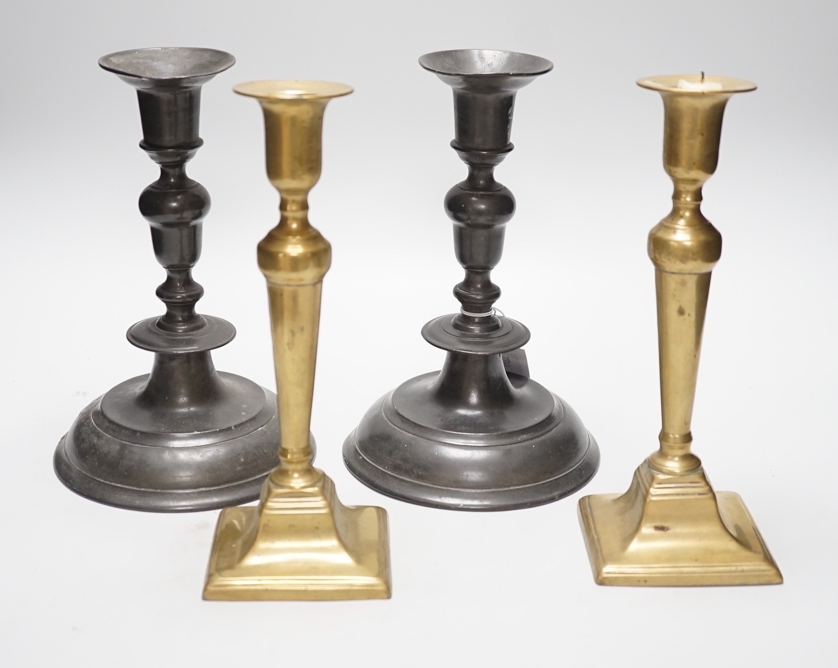 A pair of 18th century continental, possibly German, pewter candlesticks- 24cms high and a pair of late Georgian brass candlesticks